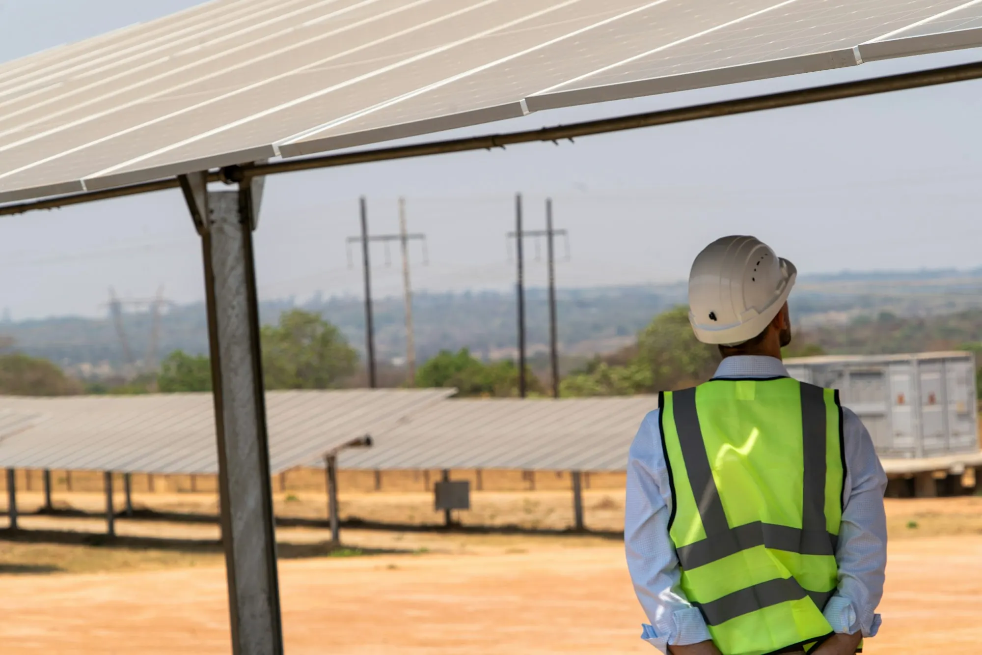 Engineer in a safety vest overlooking a large solar installation