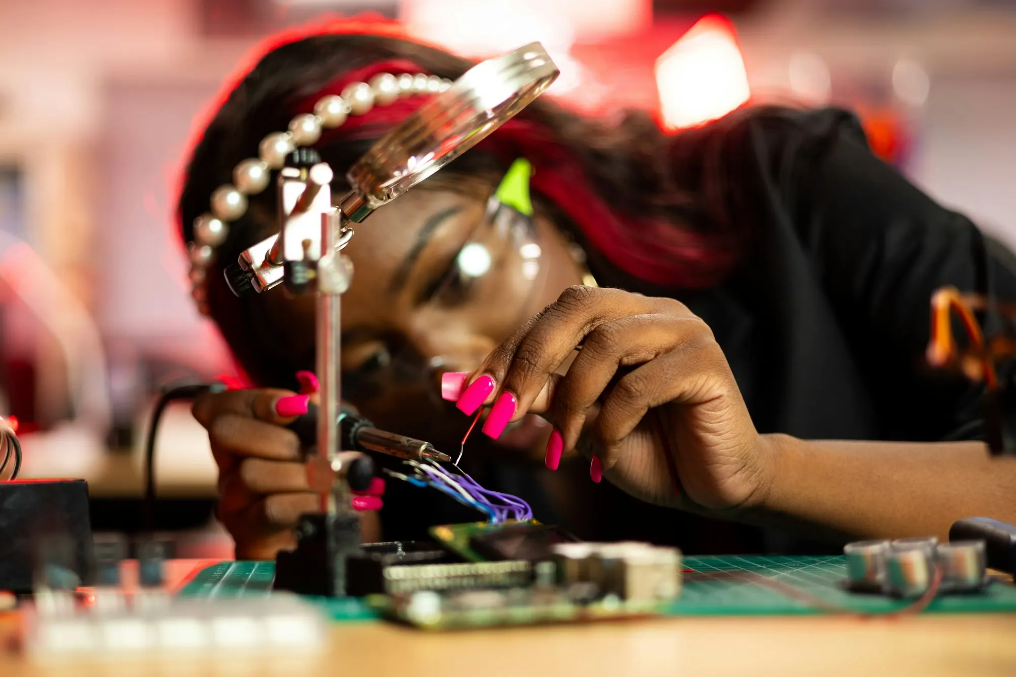 Young woman assembling a circuit board with precision tools